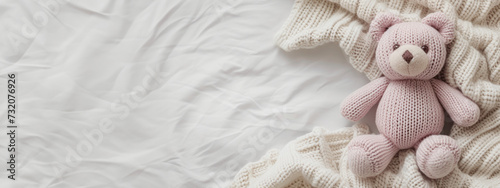 Extra wide banner flatlay image of knit plush stuffed child's toy bear in soft pink colors with blanket and flowers. Good for product mockup scene creator, text background copy space. Youth projects.