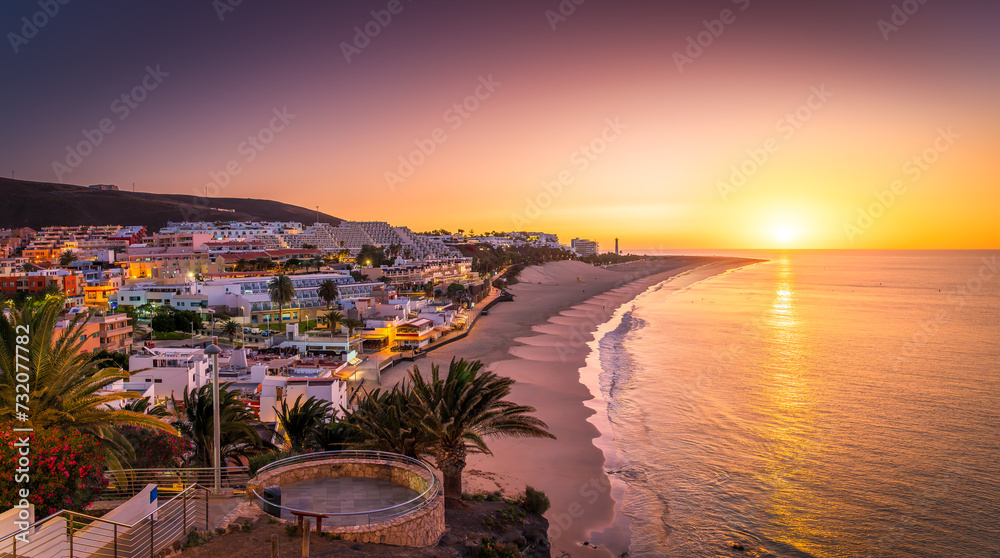 Bask in the warm glow of sunset at Morro Jable, Fuerteventura, where golden sands meet tranquil Atlantic waters—a photographer dream