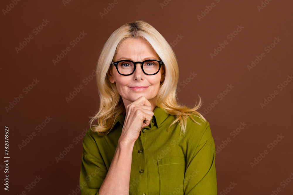 Portrait of optimistic person wear khaki outfit in eyewear hand on chin generate business ideas isolated on dark brown color background