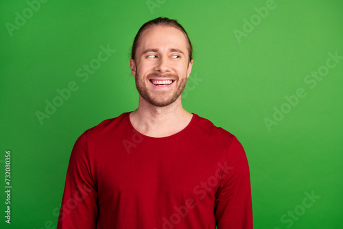 Portrait of funky guy with bristle long hairstyle wear red sweatshirt look at proposition empty space isolated on green color background