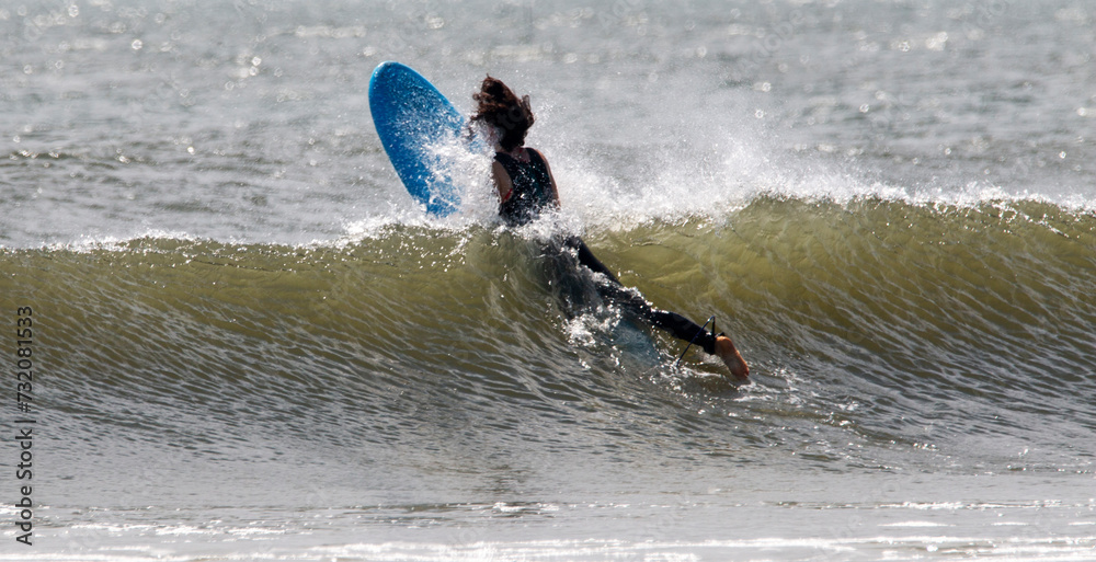 Fototapeta premium Surfer in a wetsuit splashing through a wave swimming out to go surfing