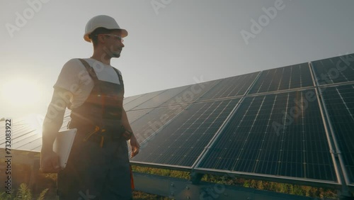 A worker walks through a solar panel station, analyzing their performance.