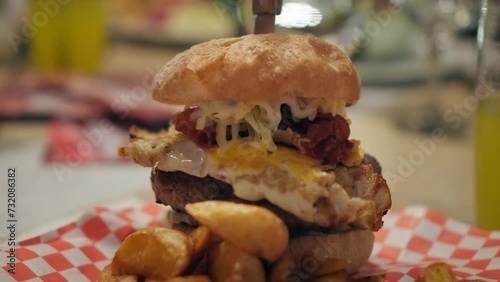 4K shot of a tasty homemade hamburger in a small american restaurant, unhealthy fast food, egg barbecue burger meal, cinematic slow motion video