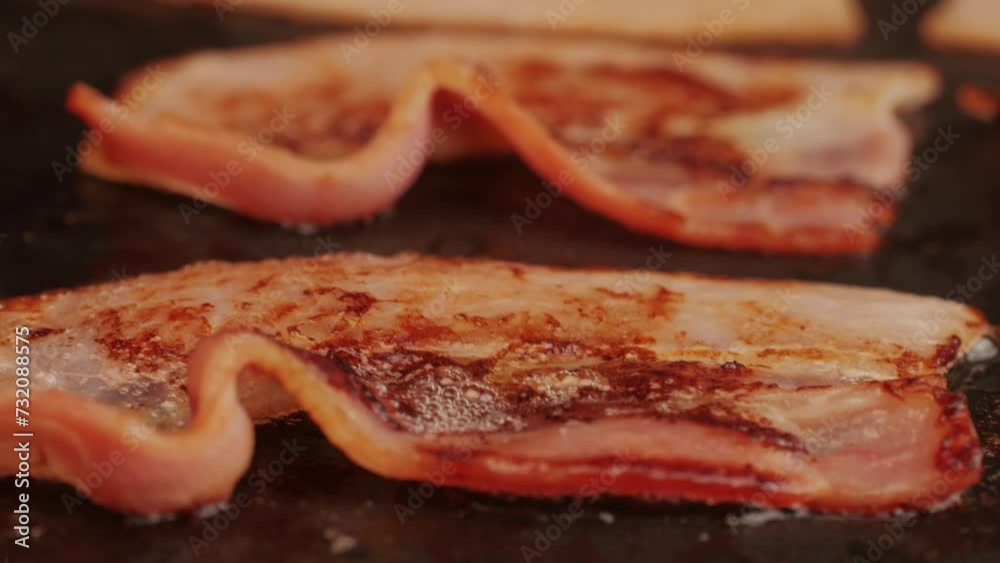 Cooking bacon slice for burgers on the grill close-up macro. The chef in kitchen of the restaurant making cutlets for smash burgers - smash burger beefsteak. Fast and street Cooking bacon slice for burgers on the grill close-up macro. The chef in kitchen of the restaurant making cutlets for smash burgers - smash burger beefsteak. Fast and street