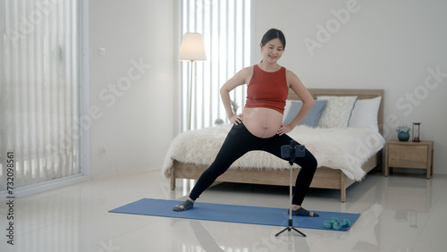 Pregnant woman doing yoga exercises on mobile phone