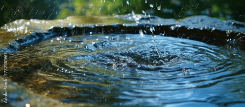 A beautiful artistic depiction of raindrops gracefully descending into a watercourse, creating ripples in the reflecting pool of liquid. © AkuAku