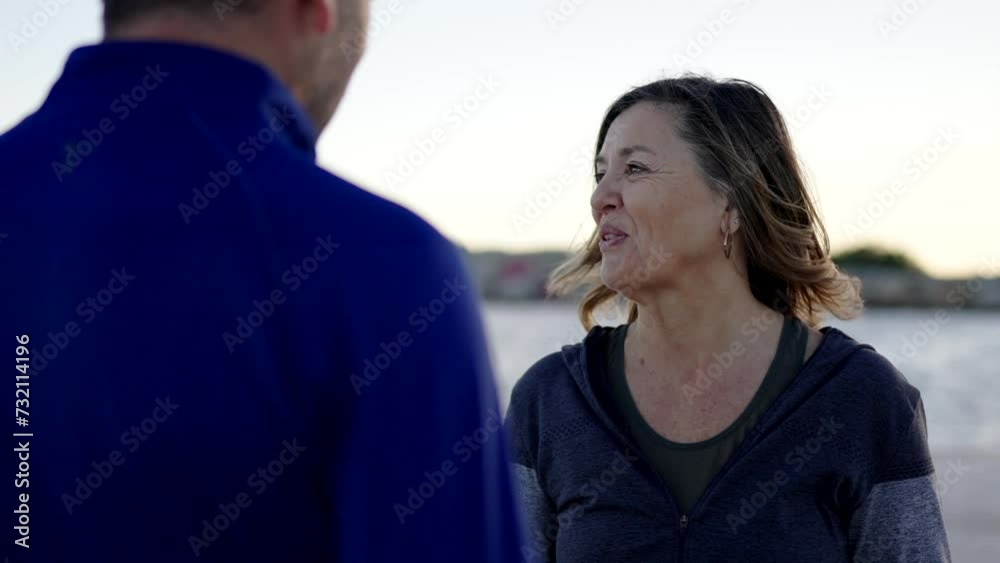 Video of a happy sportive couple laughing while chatting next to the sea during sunset Video of a happy sportive couple laughing while chatting next to the sea during sunset