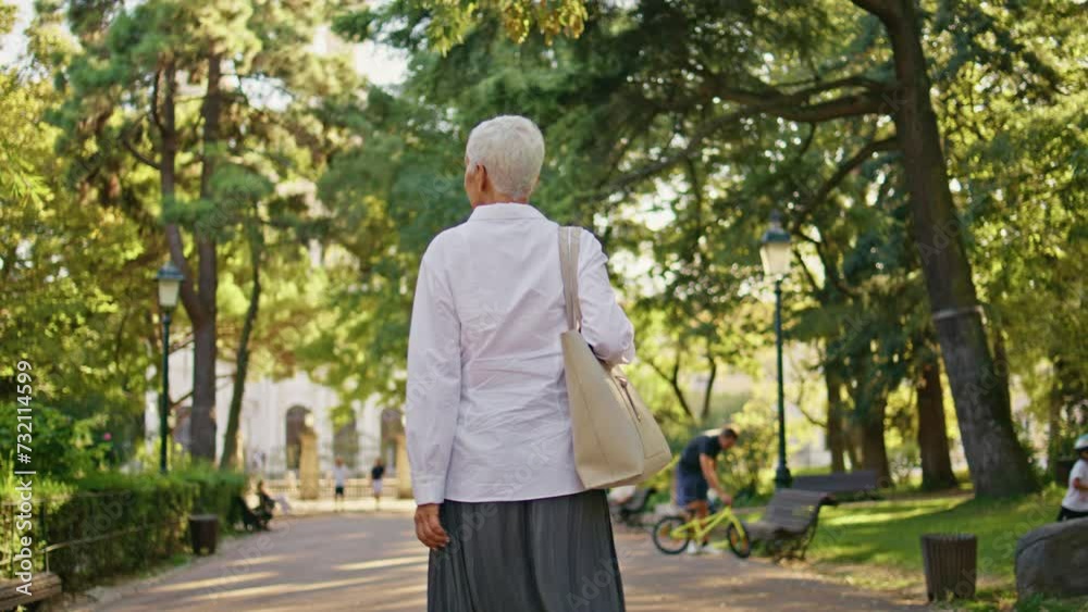 Older woman enjoying stroll in green park back view. Relaxed senior rest alone Older woman enjoying stroll in green park back view. Relaxed senior rest alone