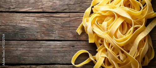 Uncooked fettuccine pasta on a wooden background, prepared for cooking.