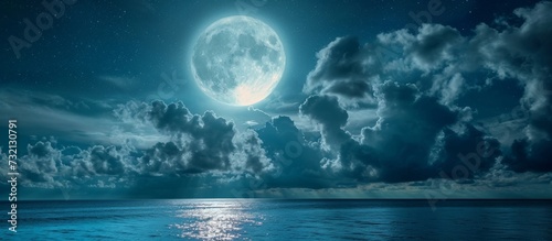 The liquid expanse of the ocean reflects the full moon rising in the night sky, creating a breathtaking natural landscape.