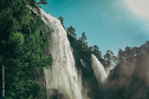 Large Hesjedalsfossen waterfall next to the road in Hordaland, Norway. Long exposure of flowing water. Water cascading down the stones in the forest. Fairy-tale and mysterious atmosphere, no people.