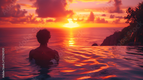 silhouette of a man at sunset in the pool  man relaxing in the infinity swimming pool looking at the ocean  a young man in the swimming pool relaxing looking out over the ocean caldera of Oia Santorin