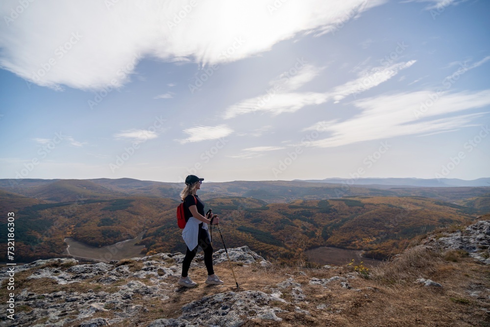 Obraz premium woman on mountain peak looking in beautiful mountain valley in autumn. Landscape with sporty young woman, blu sky in fall. Hiking. Nature