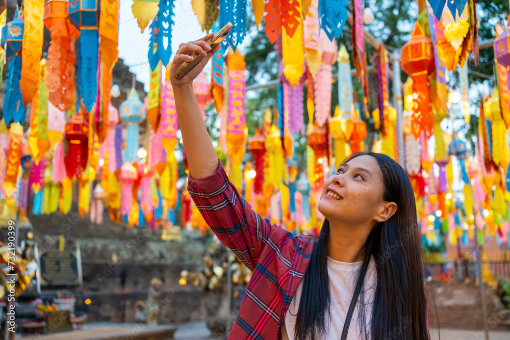 Obraz premium Asian woman tourist using mobile phone taking selfie or vlogging during travel old Buddhist temple in Chiang Mai. Attractive girl enjoy outdoor lifestyle travel Thailand on summer holiday vacation.