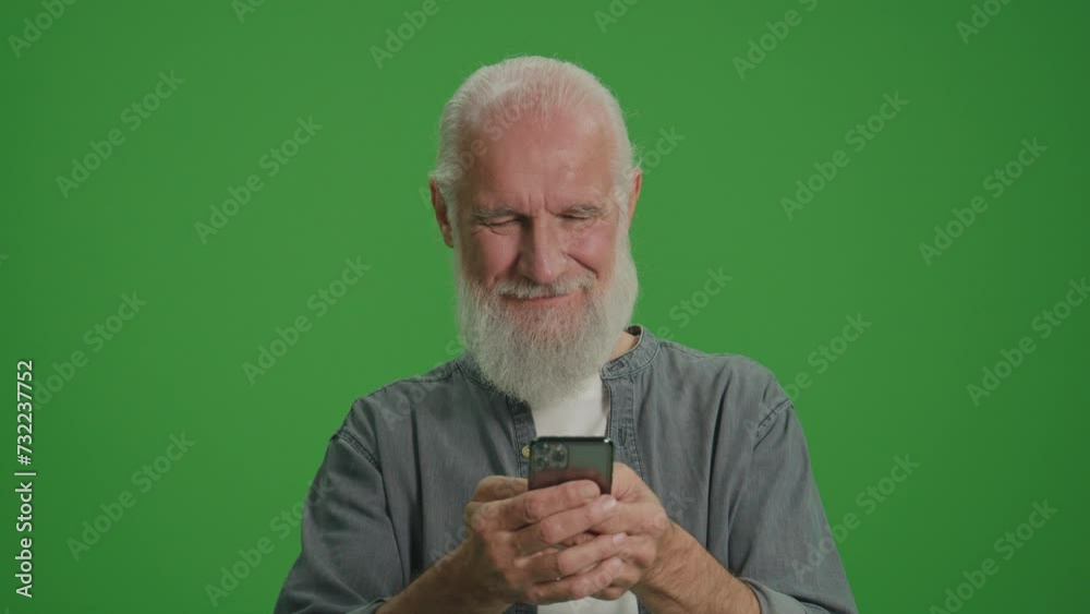 Green Screen.A Smiling Old Man with Gray Beard Scrolls on the Phone. Happy Elderly Man Shops Online. Assistive Technology for Seniors. Smart Homes and Aging in Place. Green Screen.A Smiling Old Man with Gray Beard Scrolls on the Phone. Happy Elderly Man Shops Online. Assistive Technology for Seniors. Smart Homes and Aging in Place.