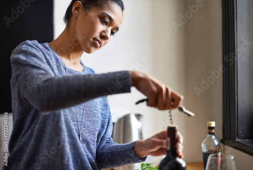 Woman, opening wine and bottle for dinner, evening meal with corkscrew and preparing to drink for enjoyment and nutrition. Alcoholic beverage, tools or equipment with cooking for dining in kitchen