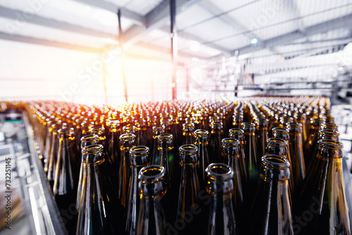 Beer brewery industry manufacturing. Brown glass bottles on conveyor belt with sunlight