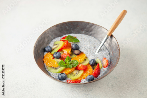Chia puddind with fruit berry salad in bowl on grey background. Healthy breakfast