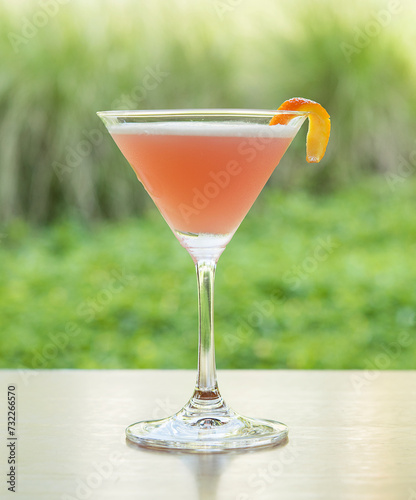 Martini glass with pink cocktail on wooden table