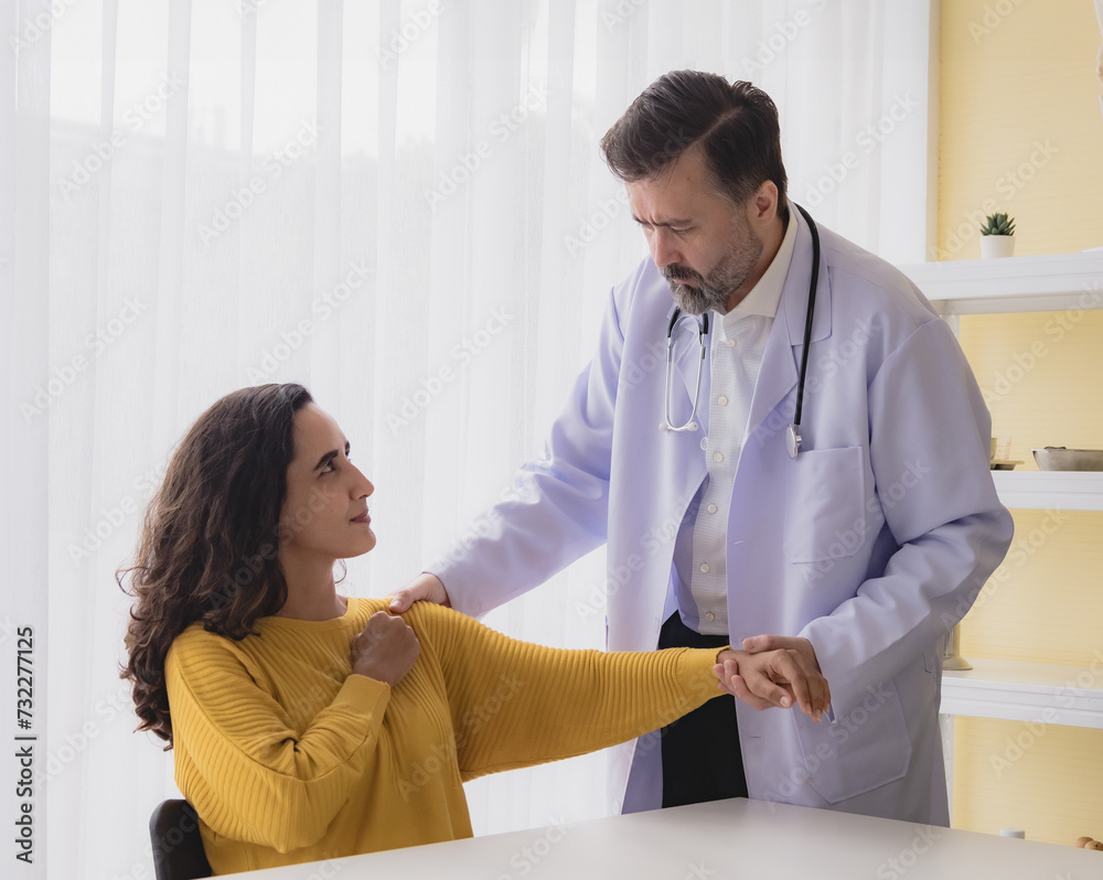 Fototapeta premium Portrait latin american woman sick injury with man doctor care caucasian physical therapist two people sitting talk helping support give advice and holding hand arm inside hospital room service