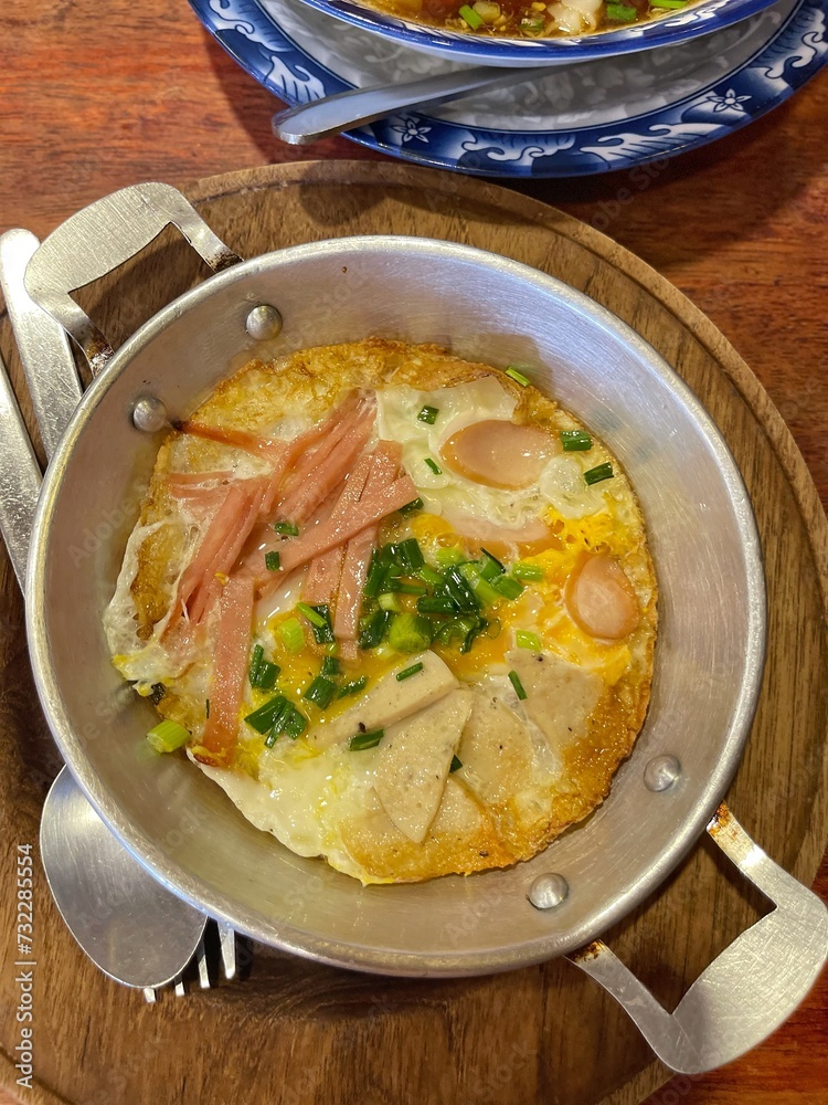 Panned eggs is fried egg topping with bacon and sausage,in the pan. Served with hot pan, famous in north eastern Thailand and Vietnam