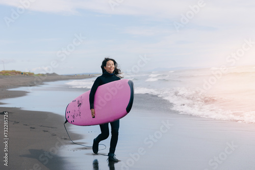 Photography Happy surfer woman in wetsuit with surfboard go to winter surfing in ocean
