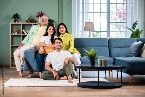 Portrait of happy Indian family of four sitting in modern living room