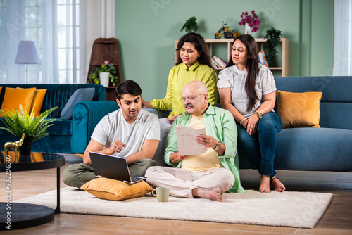 Happy indian family using laptop while sitting on sofa at home.