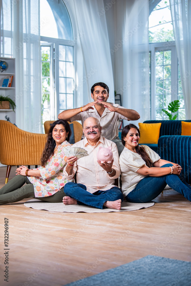 A smiling Indian family saves money with a piggy bank, looking at camera