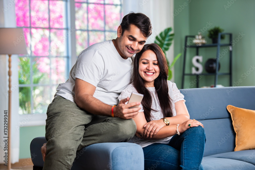 Happy and beautiful Indian Asian young couple using cellphone.