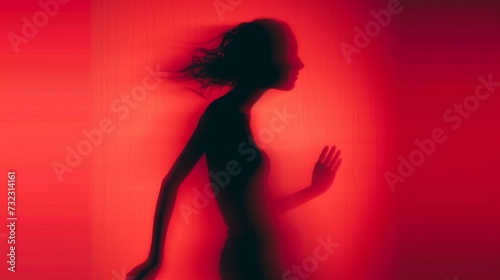 Female blurred silhouette on a red background. Elegant outline of a woman in motion out of focus