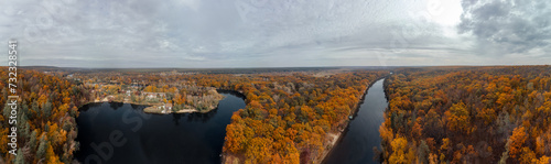 Aerial panorama of autumn river valley with colorful golden forest. Flying above vibrant trees near village in Ukraine © Kathrine Andi
