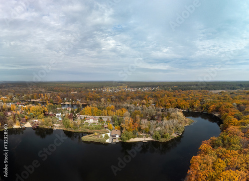 Aerial panorama of autumn river with golden trees forest. Flying above vibrant autumnal village in Ukraine © Kathrine Andi