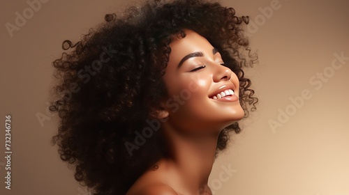 Beauty portrait of african american girl with clean healthy skin on beige background. Smiling dreamy beautiful black woman.Curly  hair in afro style