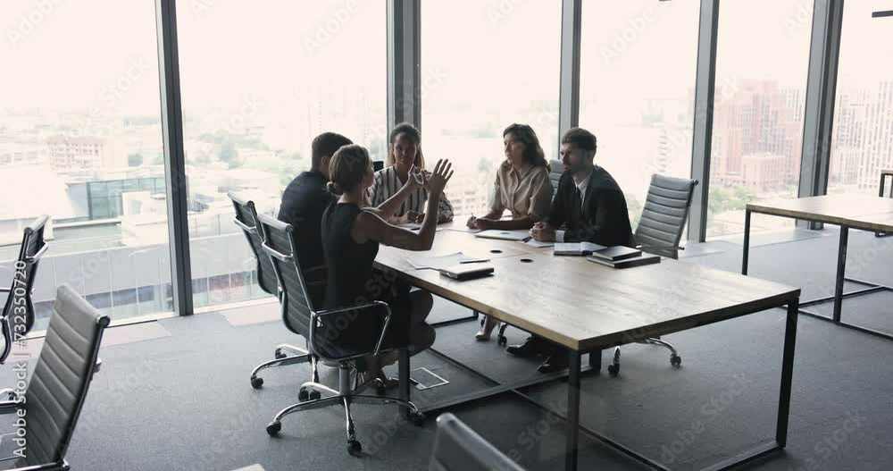Wide shot of diverse business team talking at large meeting table in contemporary modern office space with large window and city view. Office colleagues brainstorming on project Wide shot of diverse business team talking at large meeting table in contemporary modern office space with large window and city view. Office colleagues brainstorming on project