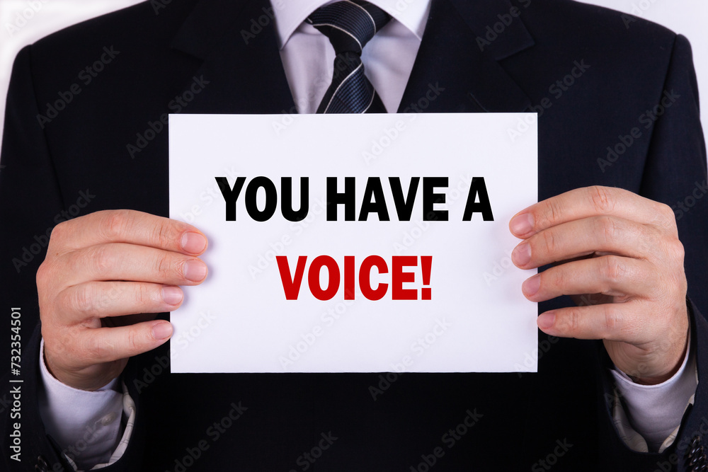 Businessman holding a card with text you have a voice Businessman holding a card with text you have a voice