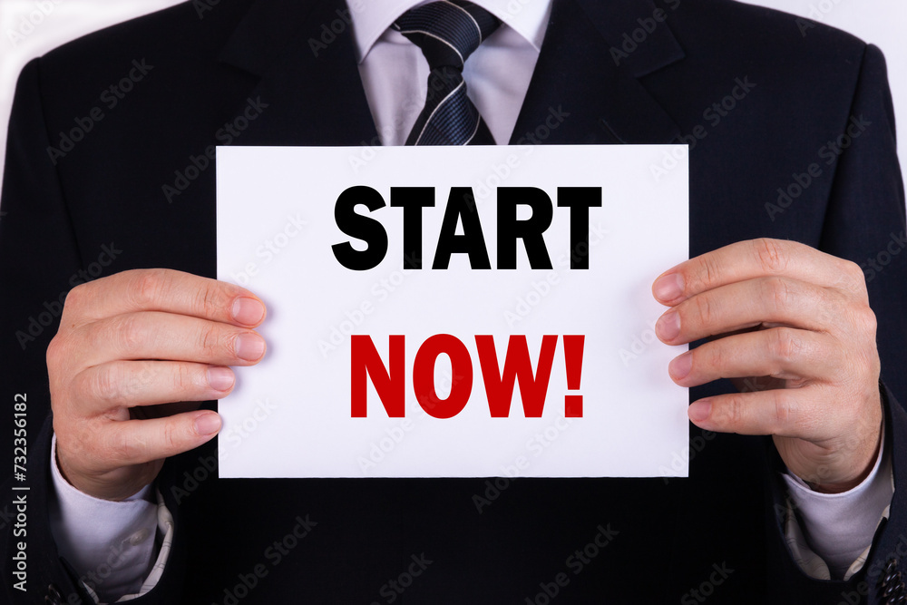 Businessman holding a card with text Start Now Businessman holding a card with text Start Now