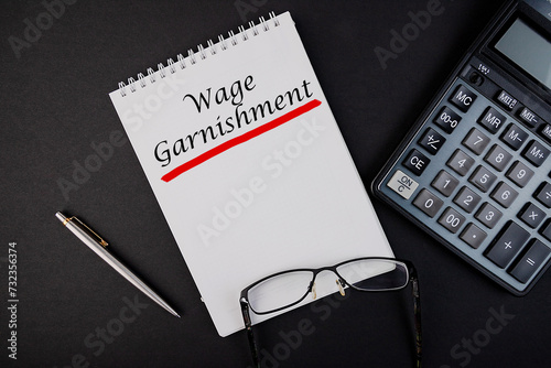 Obraz na plátně Wage Garnishment word concept written in a notebook with pen and calculator, top view