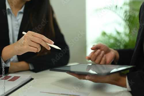 Cropped shot of businesspeople using digital tablet and analyzing marketing data during meeting