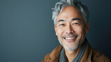 Portrait close up shot of middle aged asian male with short hair smiling in front of grey background. Portrait of a Middle Aged Asian Man Headshot.