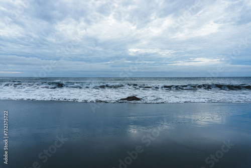 rocky coast of the atlantic ocean in moody atmosphere with black sand beach and waves  © Radu
