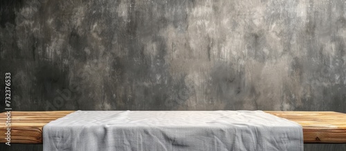 A wooden table covered by a table cloth is placed in front of a concrete wall, creating an artistic contrast between natural landscape and man-made structure.