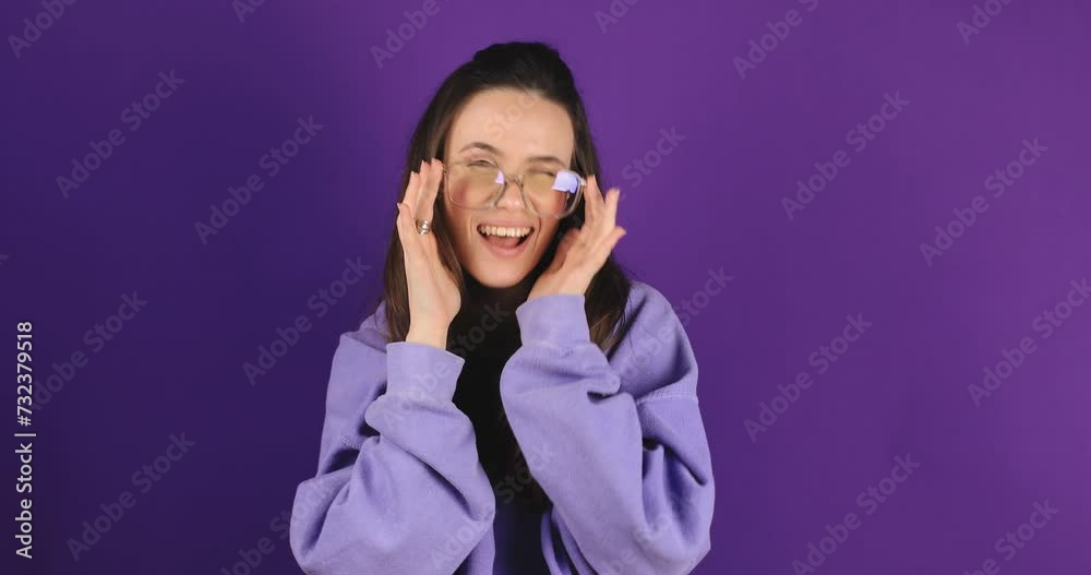 Face, wink and brunette woman with glasses, smile standing isolated on purple studio background. Portrait model with confidence, eyewear and flirty with clear vision and expression, coquette. Face, wink and brunette woman with glasses, smile standing isolated on purple studio background. Portrait model with confidence, eyewear and flirty with clear vision and expression, coquette.