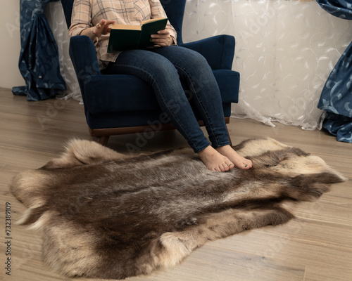 A brown deerskin on the floor in front of the chair warms women's feet on a winter day photo