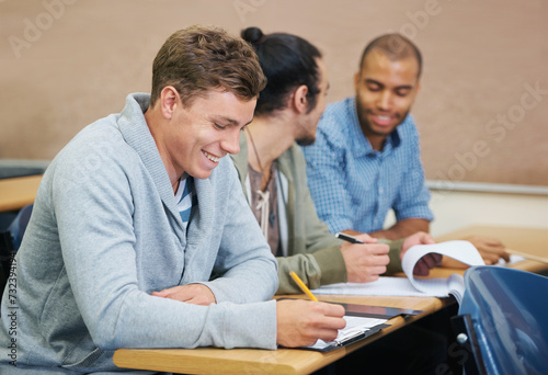 Students, university and man writing test in classroom, information and notes for studying. People, books and knowledge in education for learning, problem solving and ideas for solution in assessment