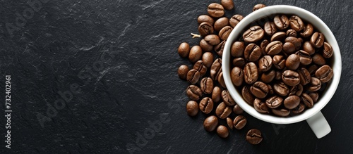 A cup filled with single-origin coffee beans, a natural food ingredient from the legume family, placed on a black table.