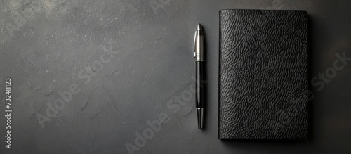 A black Communication Device and pen made of Metal are placed on a black table, creating a stylish still life composition.