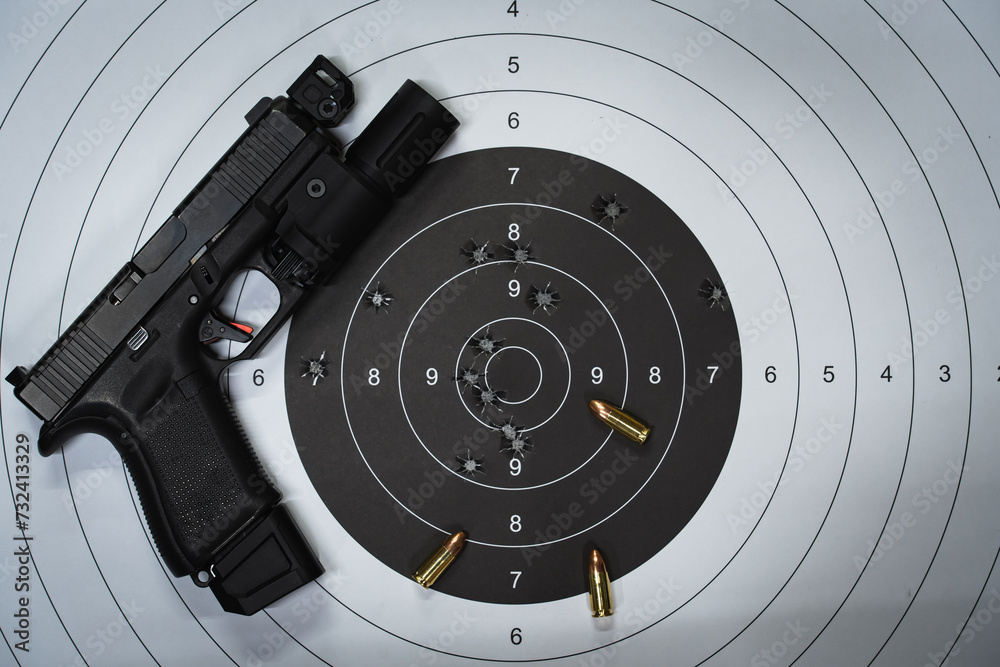 A shooting target with bullet holes in the center and a tactical pistol with a flashlight. A shooting target with bullet holes in the center and a tactical pistol with a flashlight.