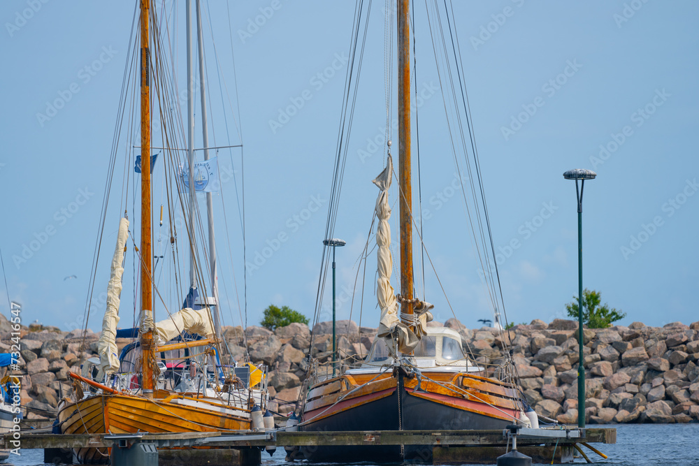Two wooden sailboats at port.