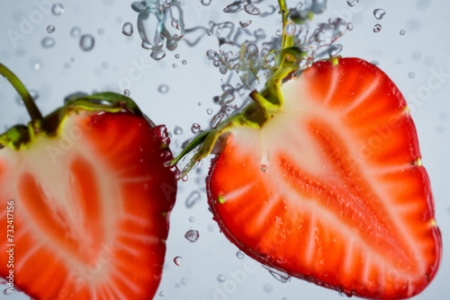 strawberry composition. halves of ripe red strawberries float in water with splashes, close-up, fruit concept